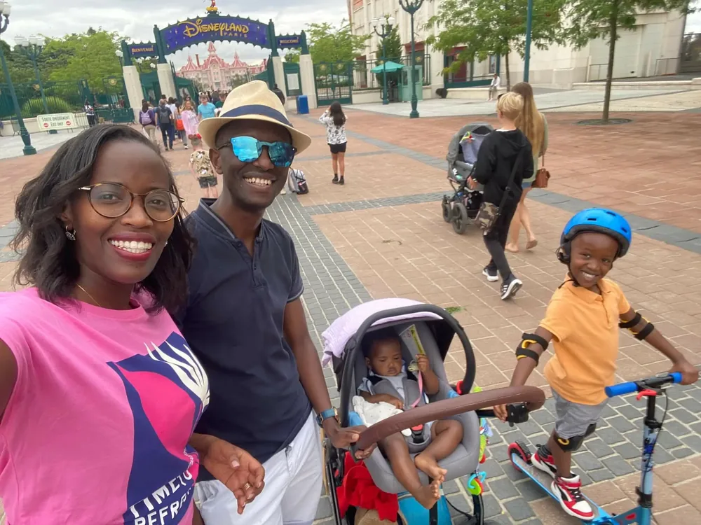 Claude Buzizi and his family smiling at the Disneyland Paris entrance.